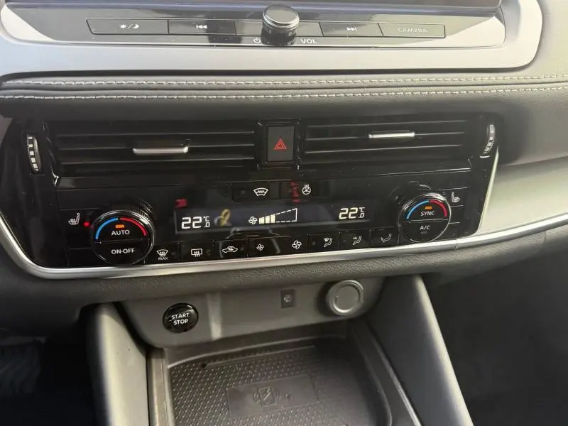 Vue rapprochée de la console centrale du Nissan Qashqai Hybrid e-POWER 2025, avec commandes climatisation et bouton start/stop.