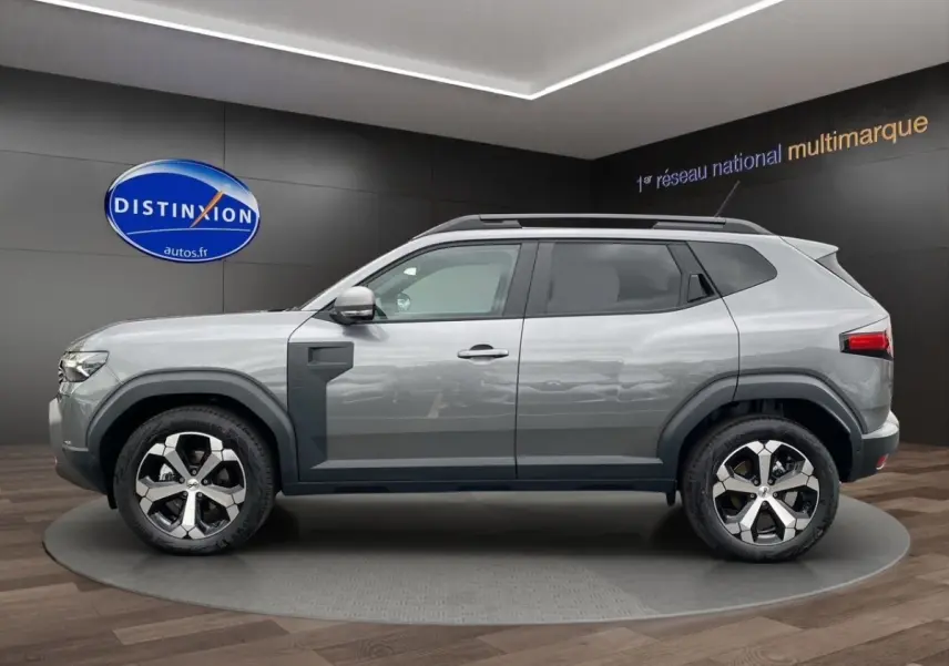 Vue latérale droite du Dacia Duster Journey Hybrid 140 gris foncé avec jantes alliage distinctives en showroom.