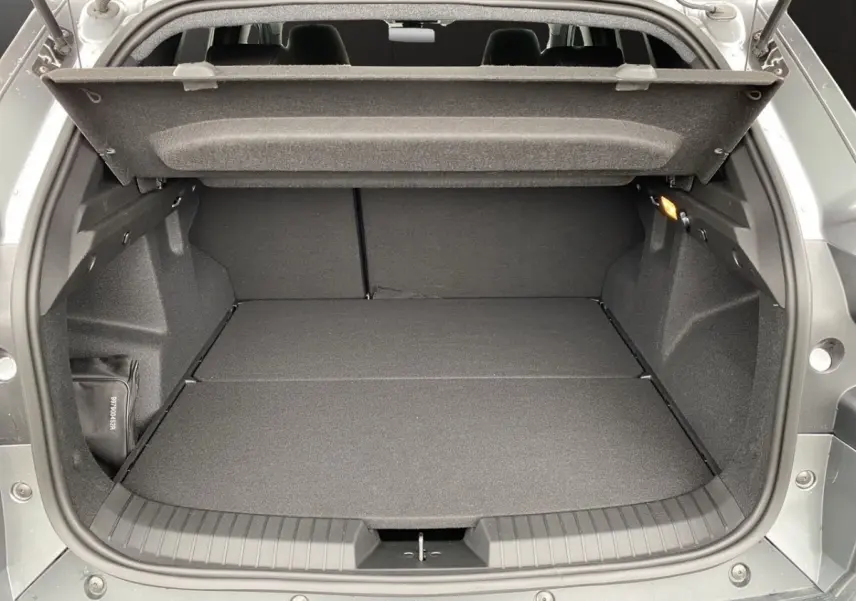Coffre ouvert gris foncé du Dacia Duster Journey Hybrid 140, vue arrière montrant un espace de chargement plat et spacieux.