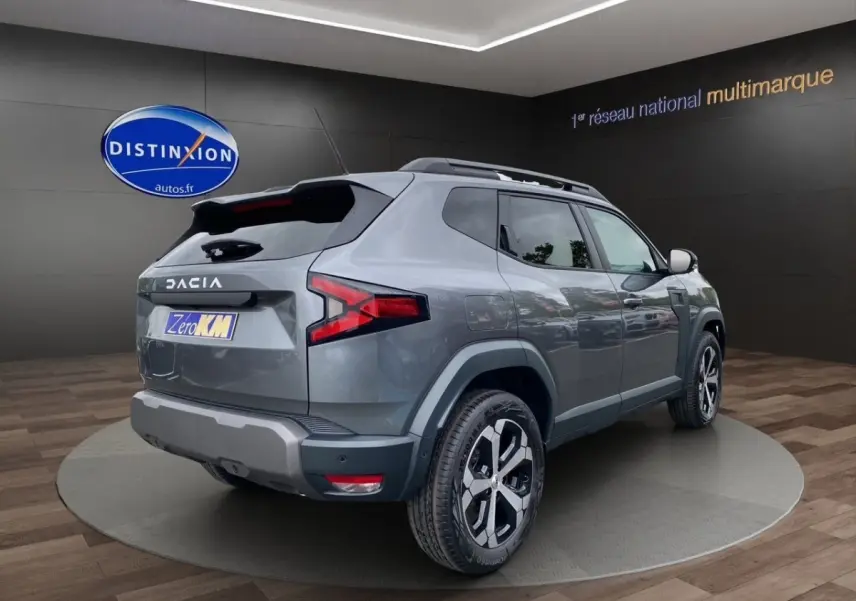 Vue 3/4 arrière droite du Dacia Duster Journey Hybrid 140 gris foncé avec jantes noires et toit noir.