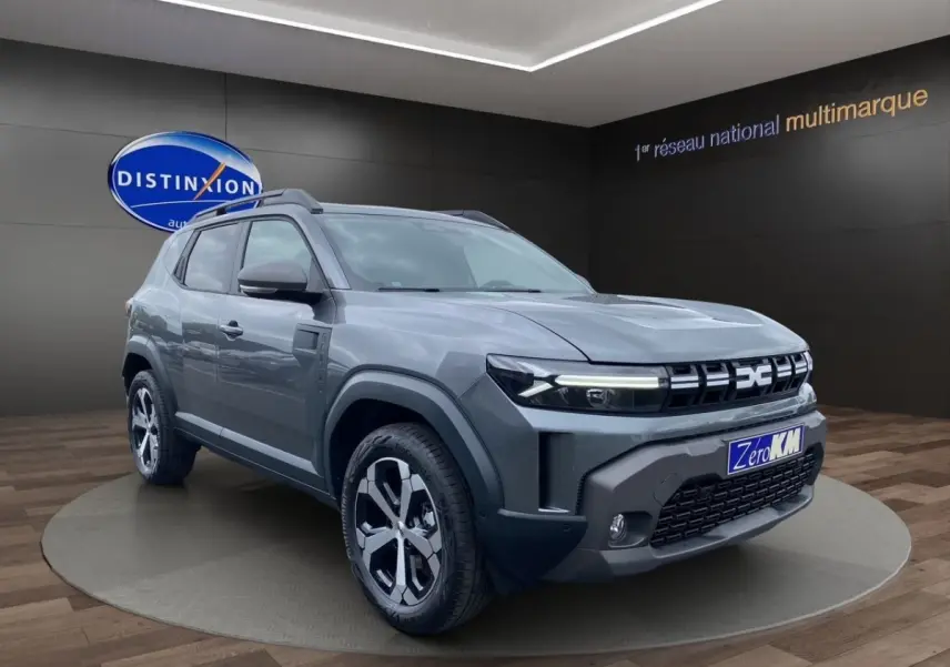SUV Dacia Duster Journey Hybrid 140 gris foncé en 3/4 avant droit avec calandre et jantes distinctives.