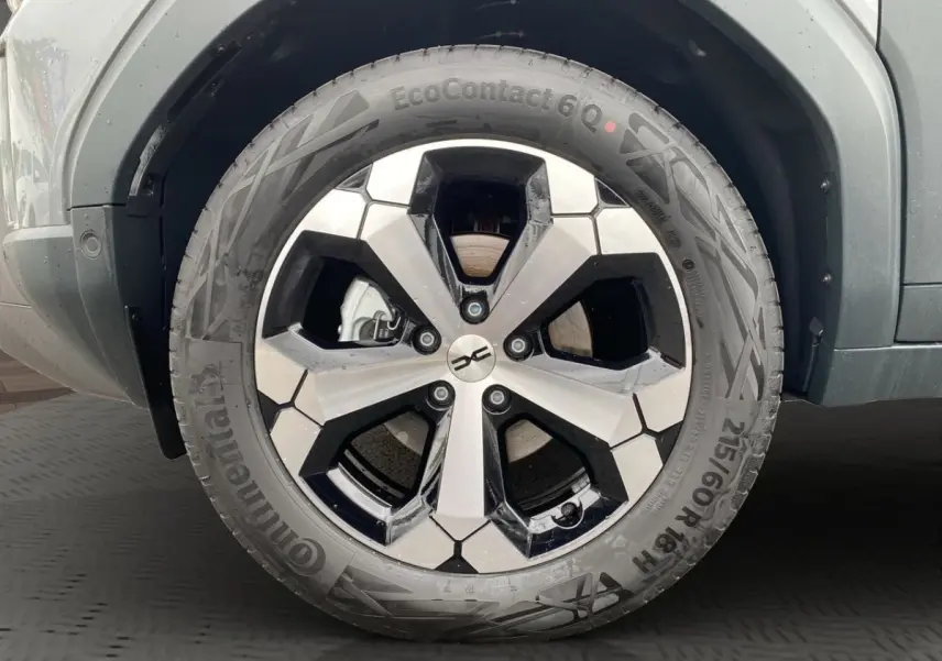 Gros plan sur la roue avant droite du Dacia Duster gris foncé, mettant en valeur la jante alliage bicolore et le pneu Continental.