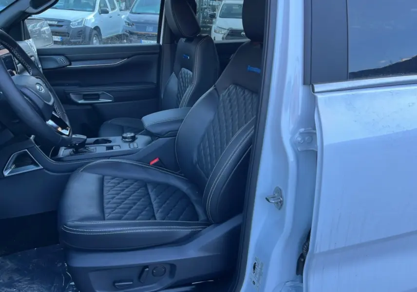Vue intérieure côté conducteur du Ford Ranger blanc glacier 2025, sièges cuir noir matelassé avec surpiqûres blanches.
