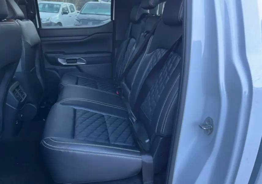 Vue côté droit arrière du Ford Ranger blanc glacier 2025, montrant les sièges arrière en cuir noir matelassé avec surpiqûres blanches.