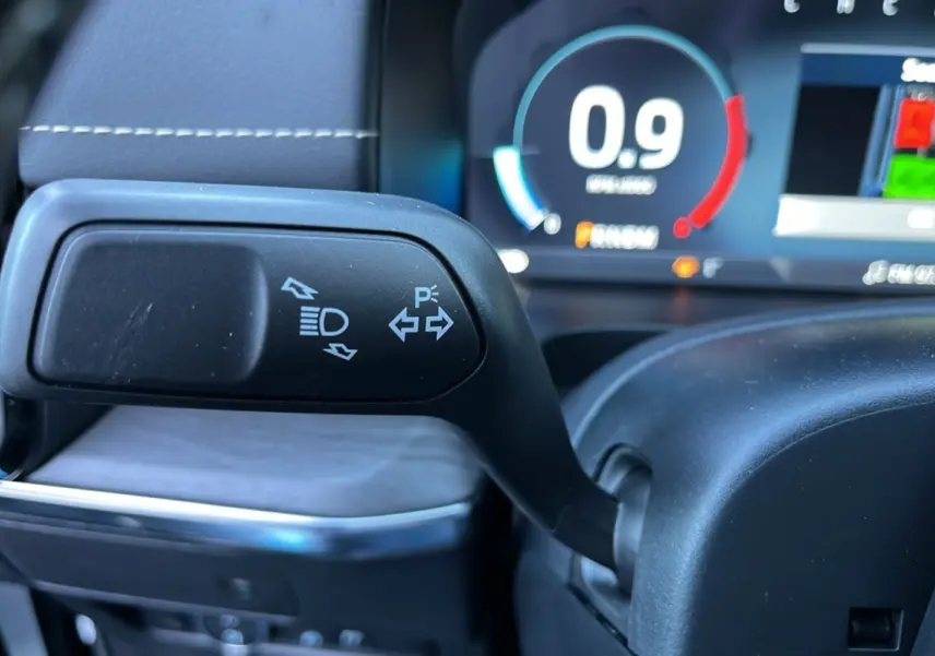 Gros plan sur la manette de clignotants et feux du Ford Ranger 3.0 V6 Platinum, avec tableau de bord numérique en arrière-plan.