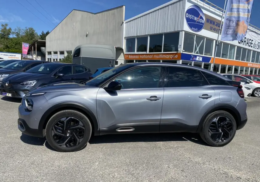 Vue de profil côté gauche d'une Citroën C4 gris foncé 2021 avec jantes noires et toit noir brillant.