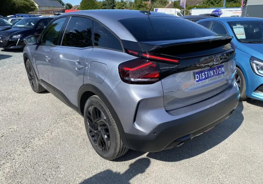 Vue 3/4 arrière droite d'une Citroën C4 gris foncé 2021 avec jantes noires et toit noir brillant.