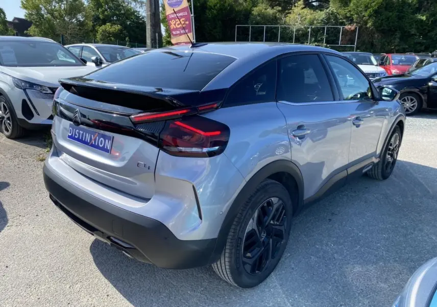 Vue 3/4 arrière droite d'une Citroën C4 gris foncé 2021 avec toit noir et jantes noires distinctives.