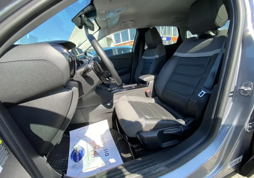 Intérieur avant droit de la Citroën C4 gris foncé 2021, sièges bi-matière avec console centrale et volant visible.