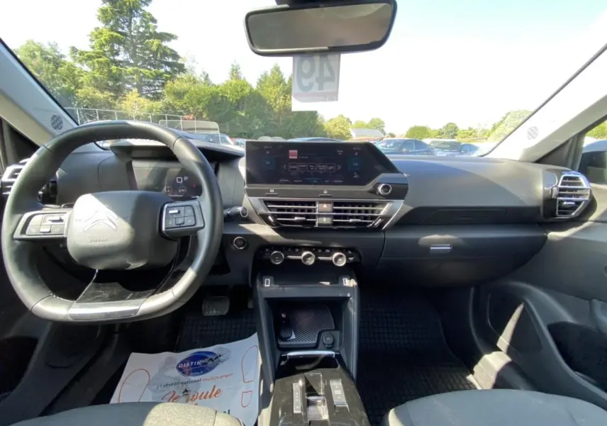 Vue intérieure avant de la Citroën C4 2021 gris foncé, montrant le tableau de bord moderne avec écran tactile central.
