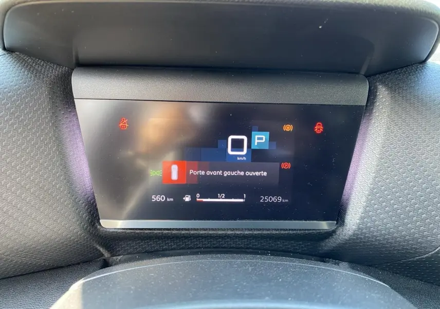 Tableau de bord numérique de Citroën C4 gris foncé 2021, affichant l'alerte porte avant gauche ouverte.