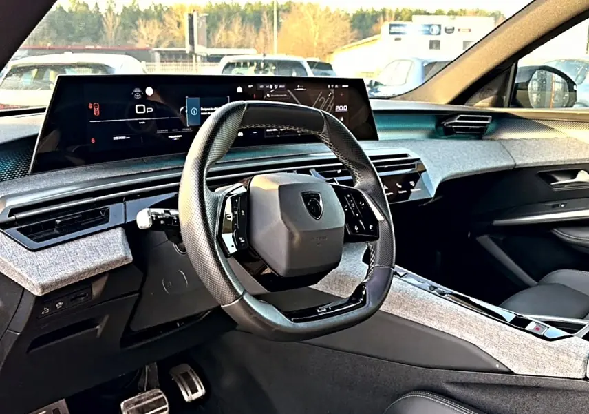 Intérieur du Peugeot 3008 gris, vue du poste de conduite avec volant cuir multifonction et écran numérique large.