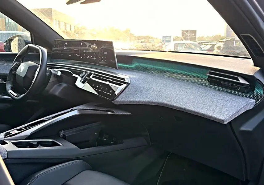 Vue intérieure côté passager du tableau de bord gris et noir du Peugeot 3008 1.2 hybrid 145 GT avec écran tactile et volant cuir.