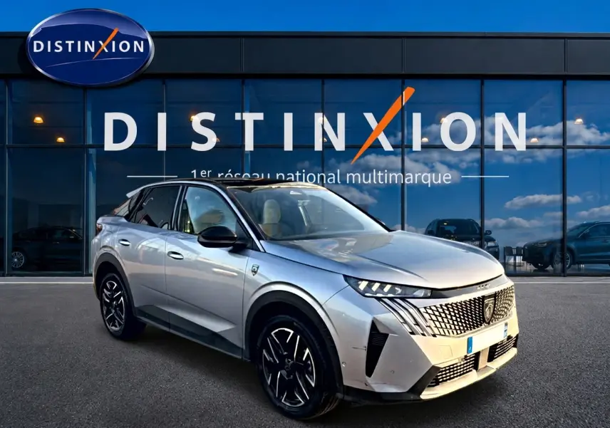 Peugeot 3008 gris en 3/4 avant droit, avec calandre distinctive et jantes alliage noires devant showroom Distinxion.