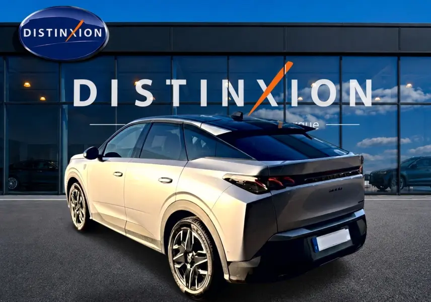 Vue 3/4 arrière droite d'un Peugeot 3008 gris 2025 avec toit noir et jantes alliage devant une vitrine Distinxion.