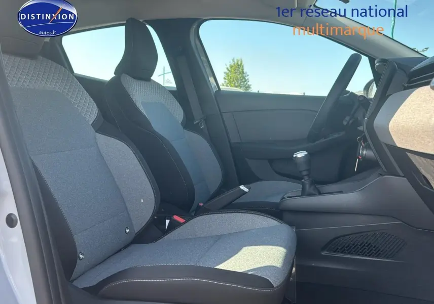Vue intérieure côté gauche de la Renault Clio V 2025, sièges tissu gris et noir avec levier de vitesse manuel visible.