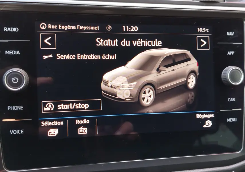 Écran de tableau de bord affichant un Volkswagen Tiguan noir en 3/4 avant avec message d'entretien à réaliser.