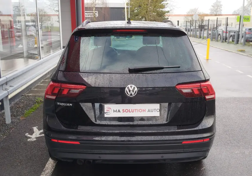 Vue arrière d'un Volkswagen Tiguan noir intense nacré 2019 avec feux arrière LED et logo VW visible sous la pluie.
