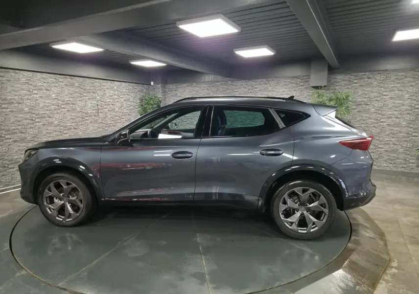 Vue de profil côté gauche d’un CUPRA Formentor gris métallisé avec jantes alliage 18'' et bas de caisse noir contrastant.