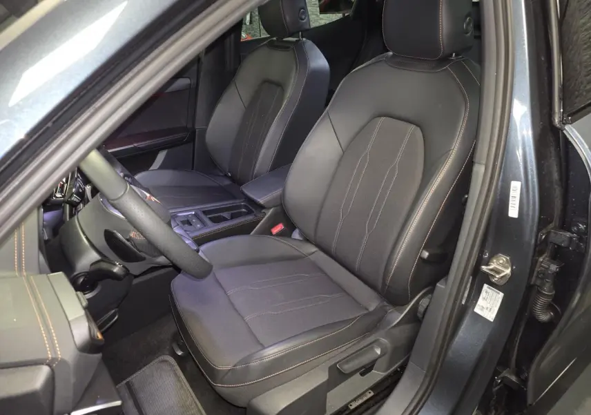 Vue intérieure côté conducteur du CUPRA Formentor gris 2025, sièges sport bimatière noirs avec surpiqûres cuivrées.