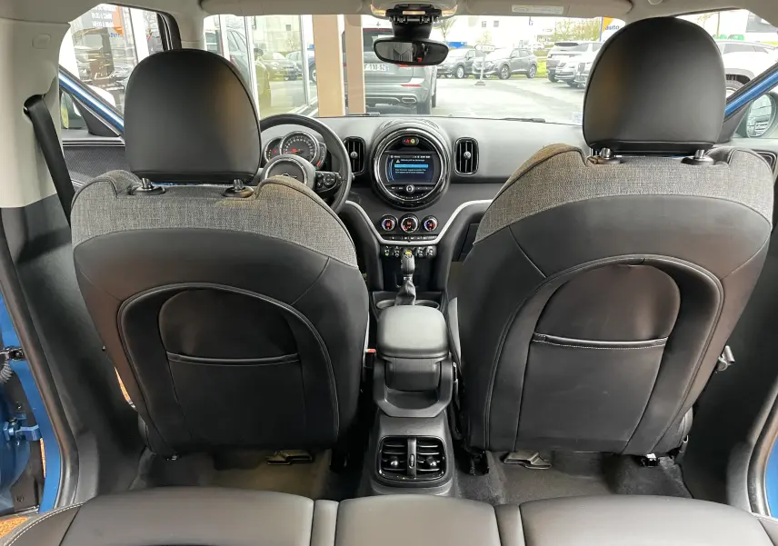 Intérieur vu depuis l'arrière d'une MINI Countryman bleu Island Metal, sièges tissu et cuir gris noir, tableau de bord moderne.