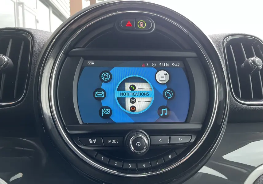 Écran central tactile rond affichant le menu notifications dans l'habitacle gris-noir du MINI Countryman hybride rechargeable.