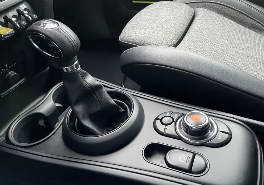 Gros plan sur la console centrale de la MINI Countryman Cooper S hybride, avec levier de vitesse et commandes circulaires.