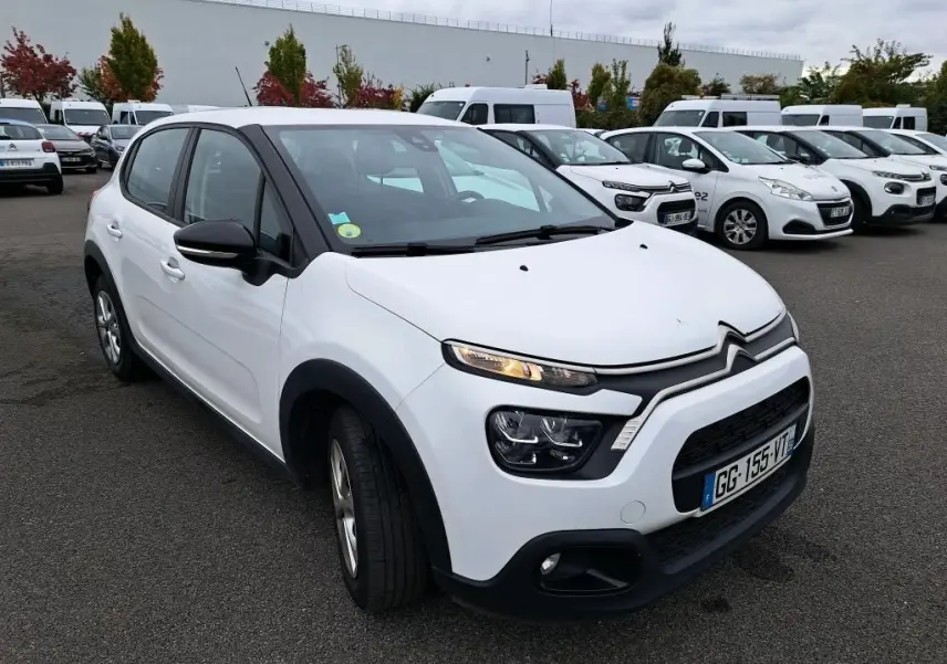 Citroën C3 Société blanche vue en 3/4 avant gauche sur parking avec calandre noire et feux allumés.