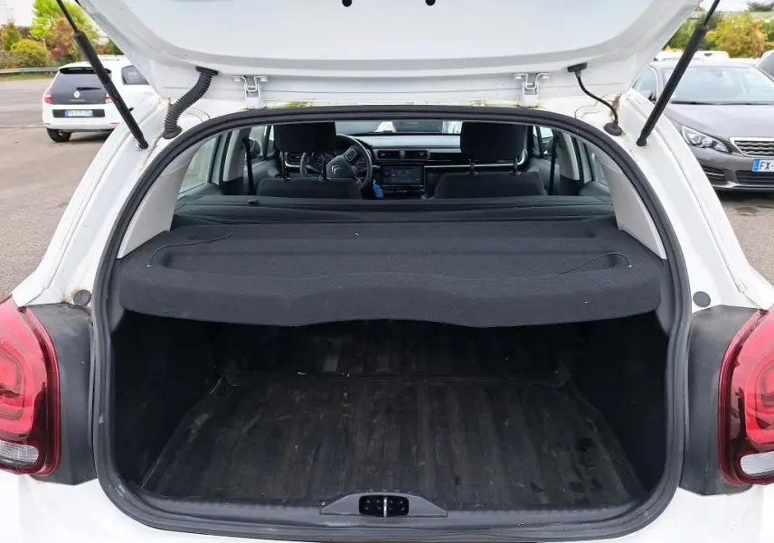 Coffre ouvert vu de l'arrière d'une Citroën C3 Société blanche, avec cache-bagages et intérieur noir visible.