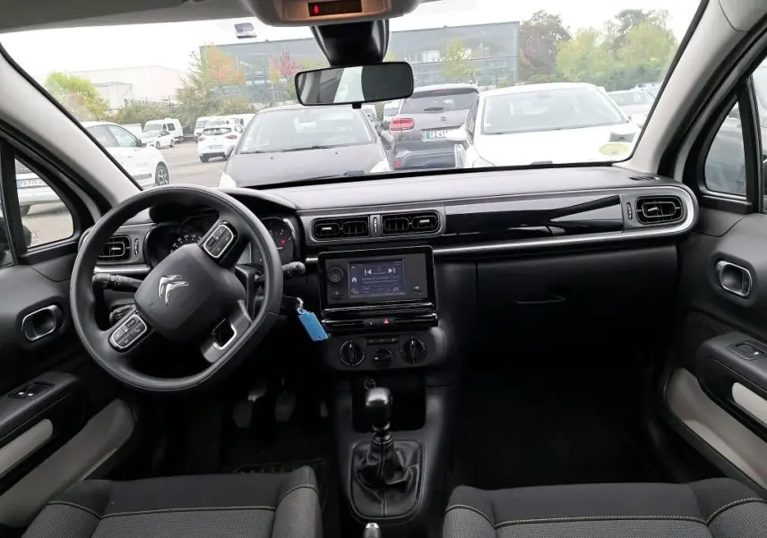 Vue intérieure avant du Citroën C3 Société blanc 2022, tableau de bord noir avec écran tactile et volant multifonction.