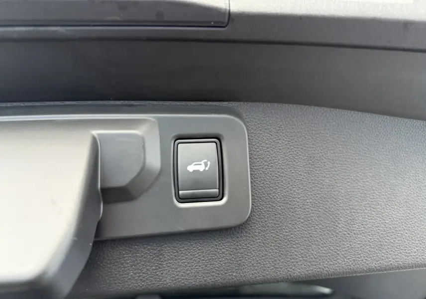 Gros plan sur le bouton d'ouverture du coffre dans l'habitacle du Renault Symbioz gris Rafale 2025.