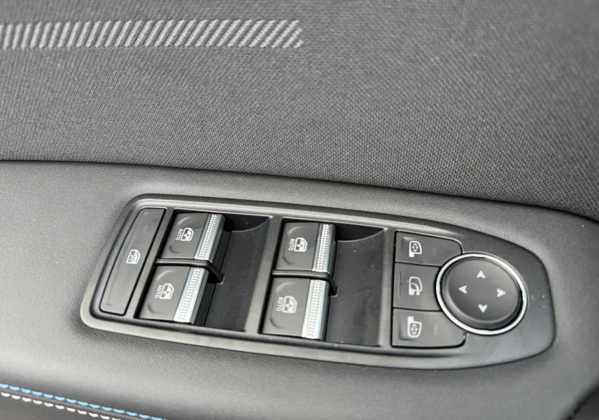 Gros plan sur les commandes des vitres et rétroviseurs côté gauche d’une Renault Symbioz gris rafale, 2025.