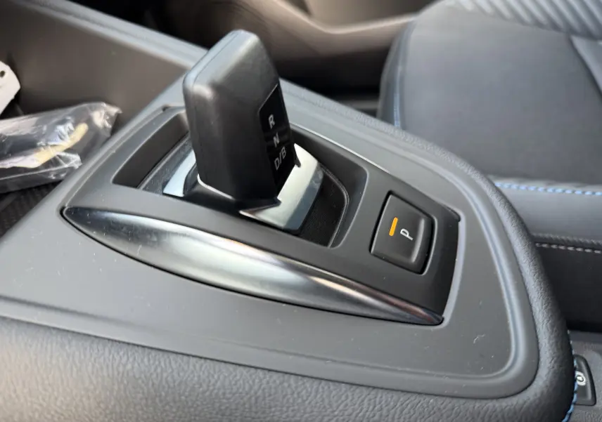 Gros plan sur le levier de vitesse automatique noir et bouton de parking orange dans l’habitacle gris du Renault Symbioz 2025.