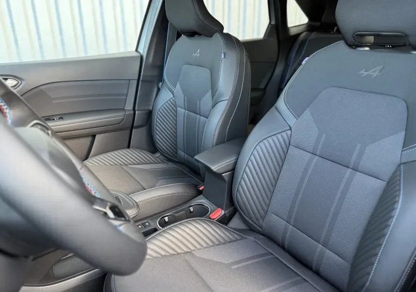 Vue intérieure sur les sièges avant gris avec logo Alpine embossé, volant partiellement visible côté gauche du Renault Symbioz 2025.