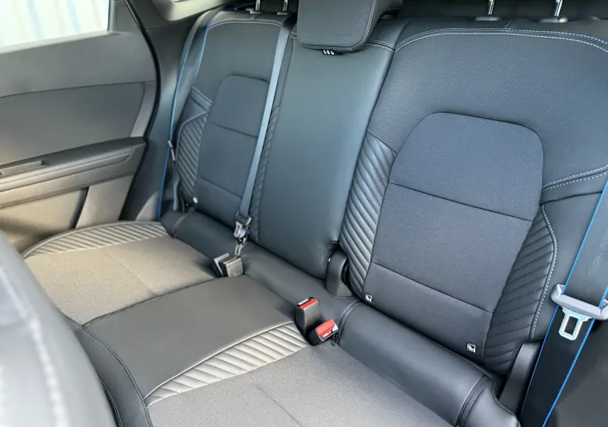 Vue rapprochée des sièges arrière noirs et gris du Renault Symbioz 2025 avec surpiqûres bleues et ceintures assorties.
