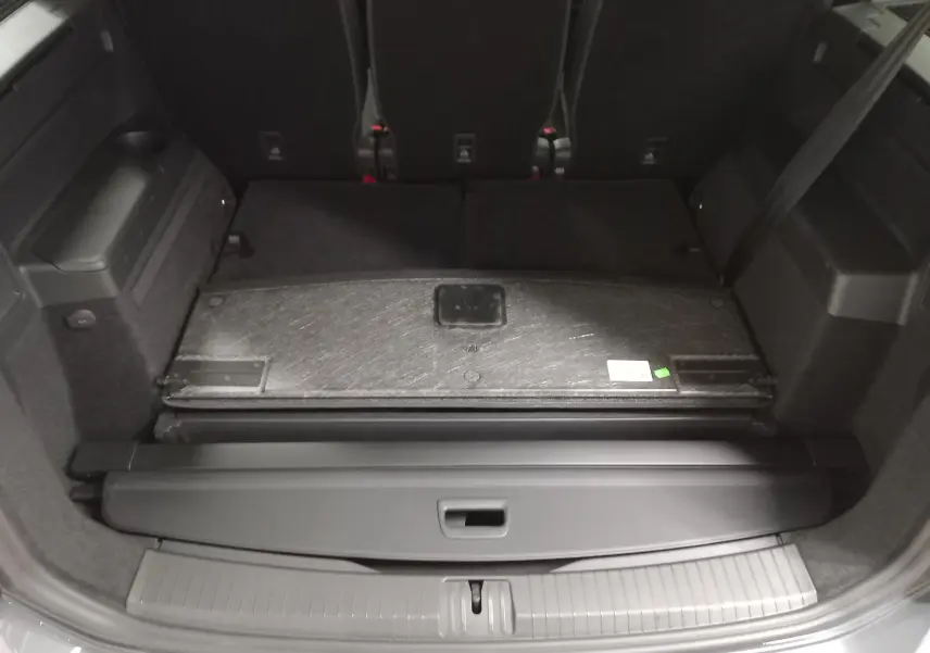 Vue intérieure du coffre du Volkswagen Touran 2025 gris Dauphin, avec banquette arrière rabattue et cache-bagages visible.