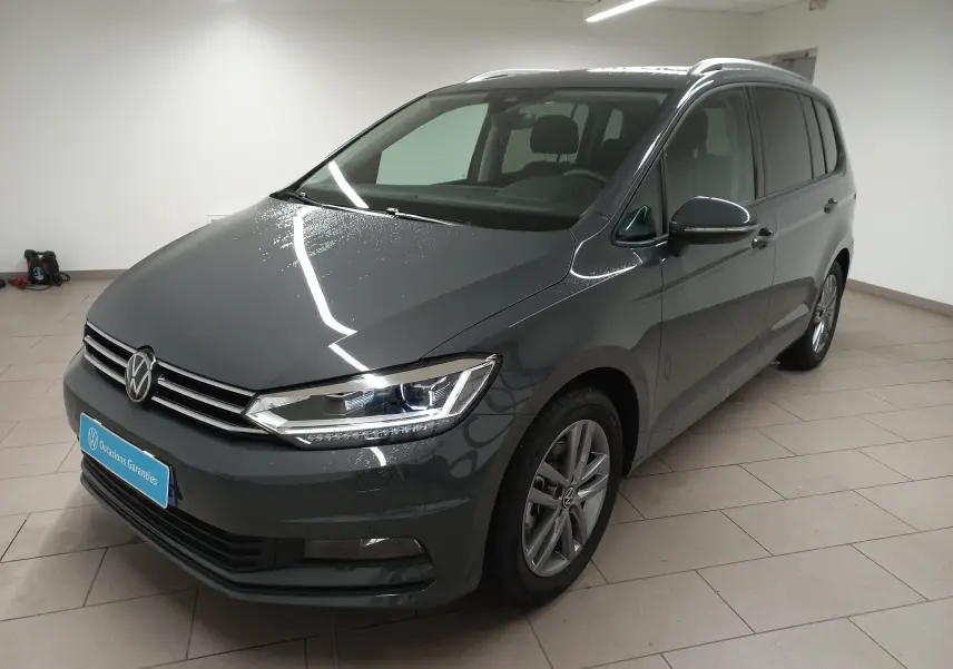 Volkswagen Touran 2025 gris dauphin en 3/4 avant droit, avec phares LED et jantes alliage visibles.