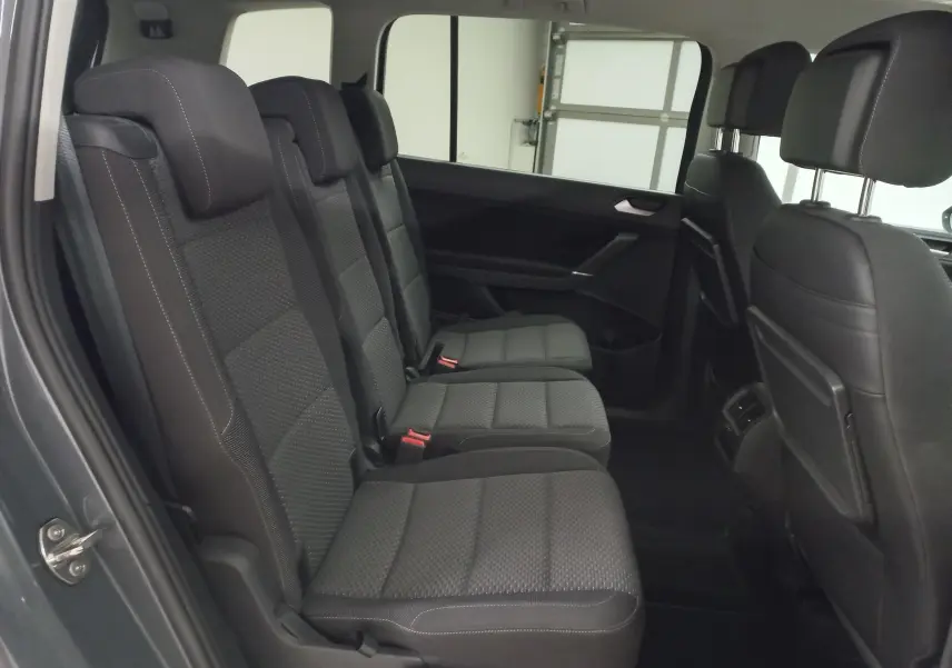 Vue intérieure côté gauche des sièges arrière en tissu gris foncé du Volkswagen Touran 2025, version 7 places.