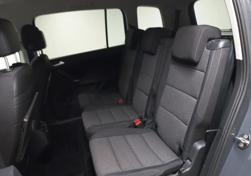 Vue intérieure côté droit des sièges arrière en tissu gris du Volkswagen Touran 2025 Gris Dauphin, version 7 places.