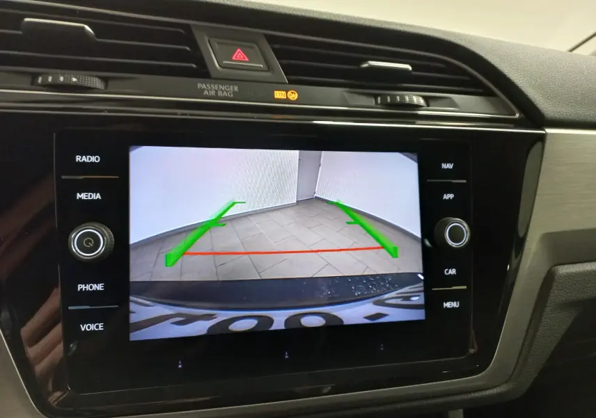 Écran central affichant la caméra de recul du Volkswagen Touran 2025 avec repères verts et rouge sur sol carrelé.