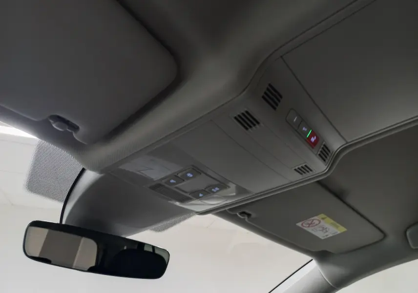 Vue intérieure du plafond avec commandes d'éclairage et rétroviseur dans un Volkswagen Touran gris Dauphin 2025.