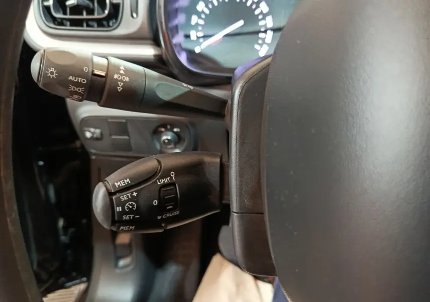 Gros plan sur le volant noir de la Citroën C3 2024 avec commandes de régulateur et commodo d’éclairage.