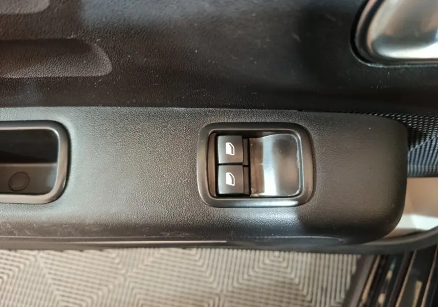 Gros plan sur les commandes des vitres électriques côté conducteur de la Citroën C3 noire 2024.