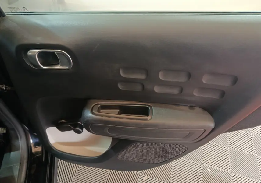 Vue rapprochée de la porte intérieure côté gauche noire de la Citroën C3 2024 avec poignée et haut-parleur intégrés.