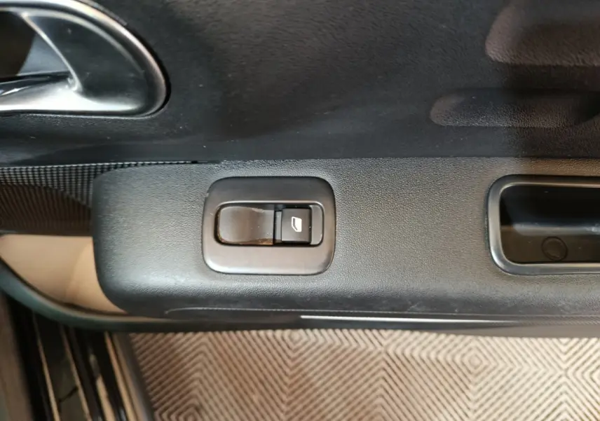 Gros plan sur le bouton de commande de la vitre électrique côté conducteur de la Citroën C3 noire 2024.