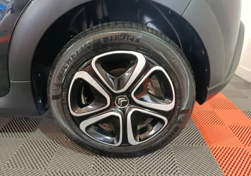 Gros plan sur la roue avant droite noire d'une Citroën C3 2024 avec jante alliage au design moderne.