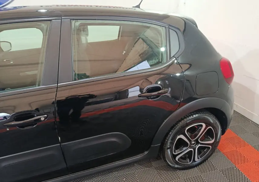 Vue latérale côté droit de la Citroën C3 noire 2024, mettant en valeur la porte arrière et la roue au design distinctif.