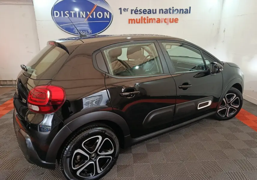 Citroën C3 noire vue 3/4 arrière droit, avec jantes alliage distinctives et protections latérales blanches.