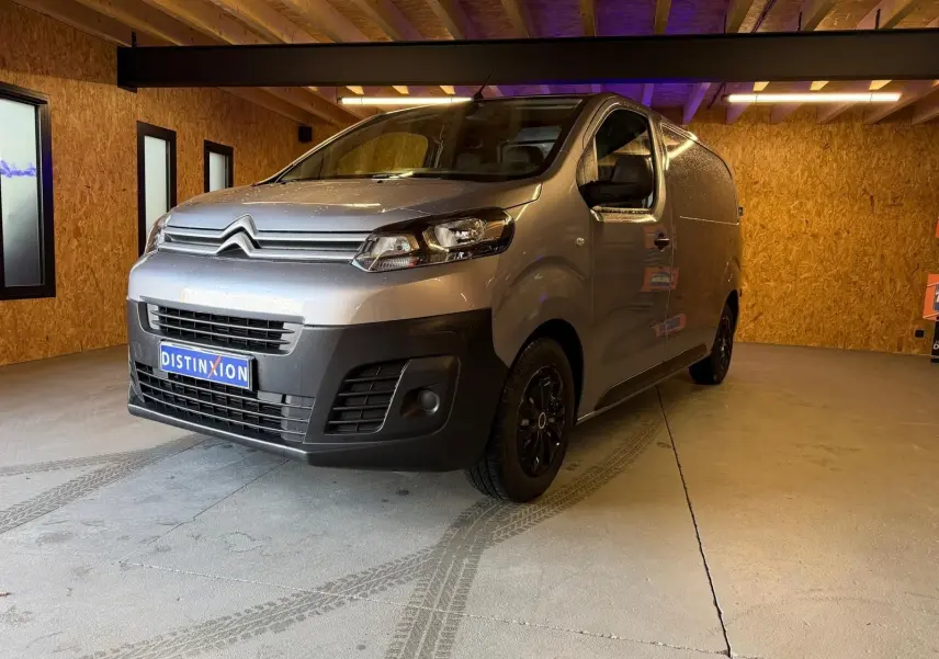 Vue 3/4 avant droit d'un Citroën Jumpy gris métallisé 2022 dans un garage en bois, avec calandre noire et jantes foncées.