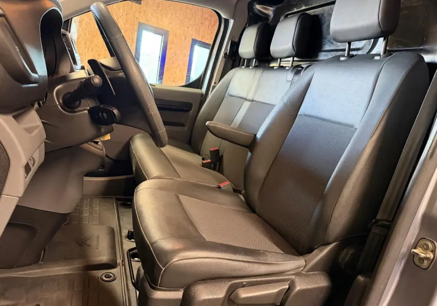 Vue intérieure côté conducteur du Citroën Jumpy gris 2022, montrant les sièges en cuir et le volant.